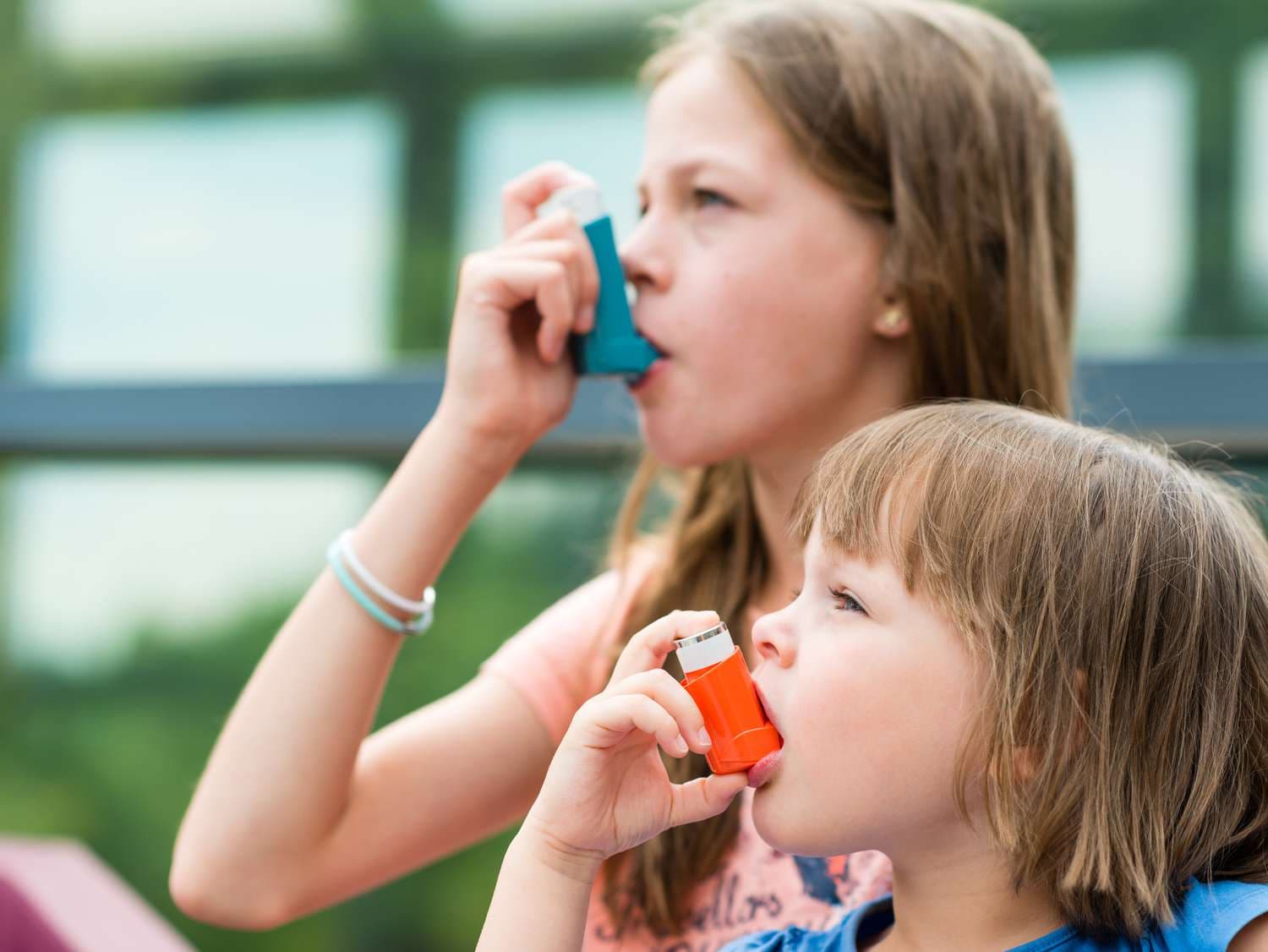 Two children using inhalers outdoors