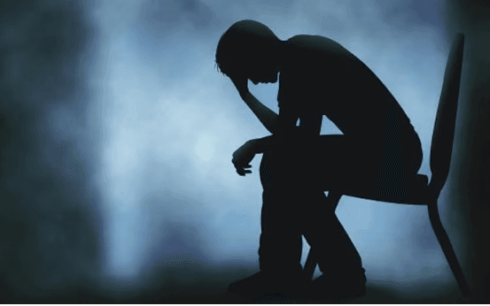 Silhouette of a person sitting with head bowed, representing depression