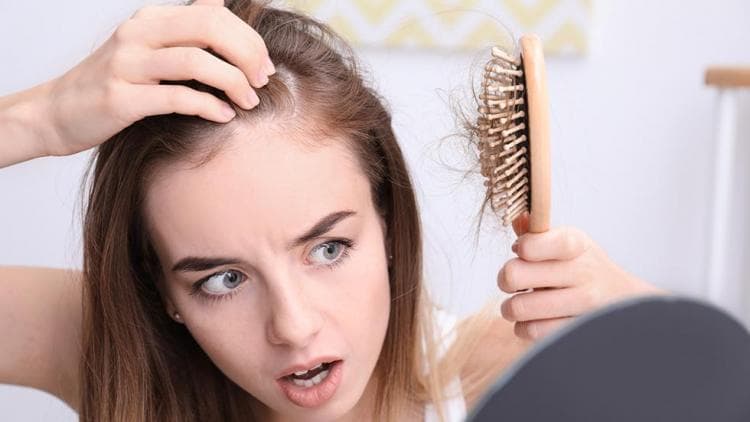 A woman examining thinning hair with a hairbrush